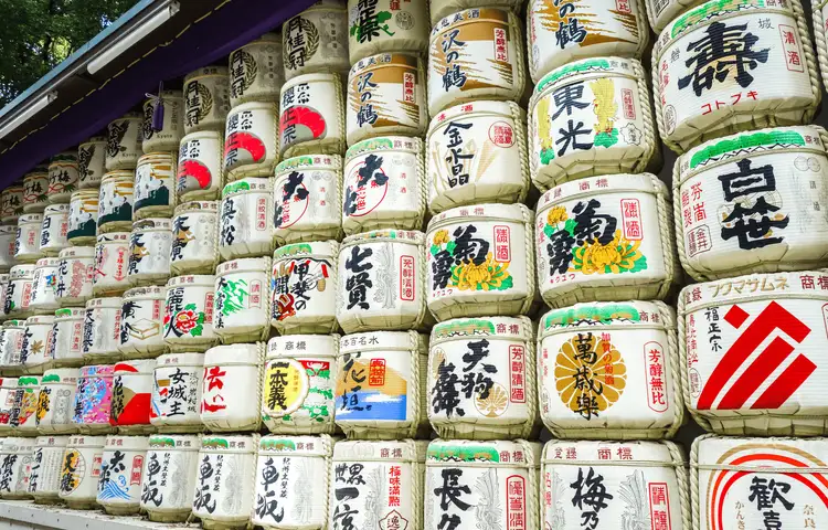 Splendeur de l'automne au jardin Shinjuku Gyoen à Tokyo avec les érables rouges (Momiji) et la tour NTT Docomo en arrière-plan, une expérience de voyage zen recommandée par Shanti Travel.