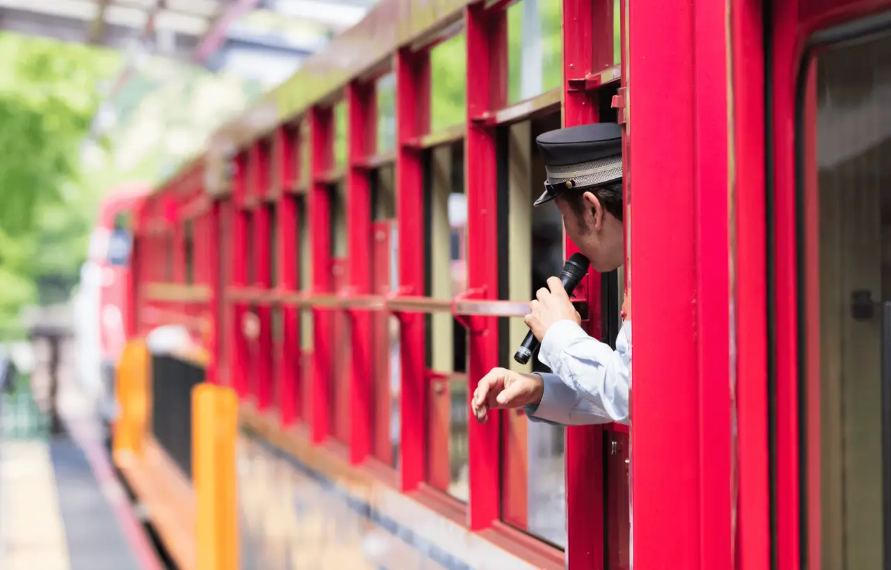 Contrôleur japonais annonçant les paysages de la rivière Hozugawa à bord du Sagano Romantic Train à Arashiyama, une immersion nostalgique et panoramique incluse dans le circuit ferroviaire de Shanti Travel.