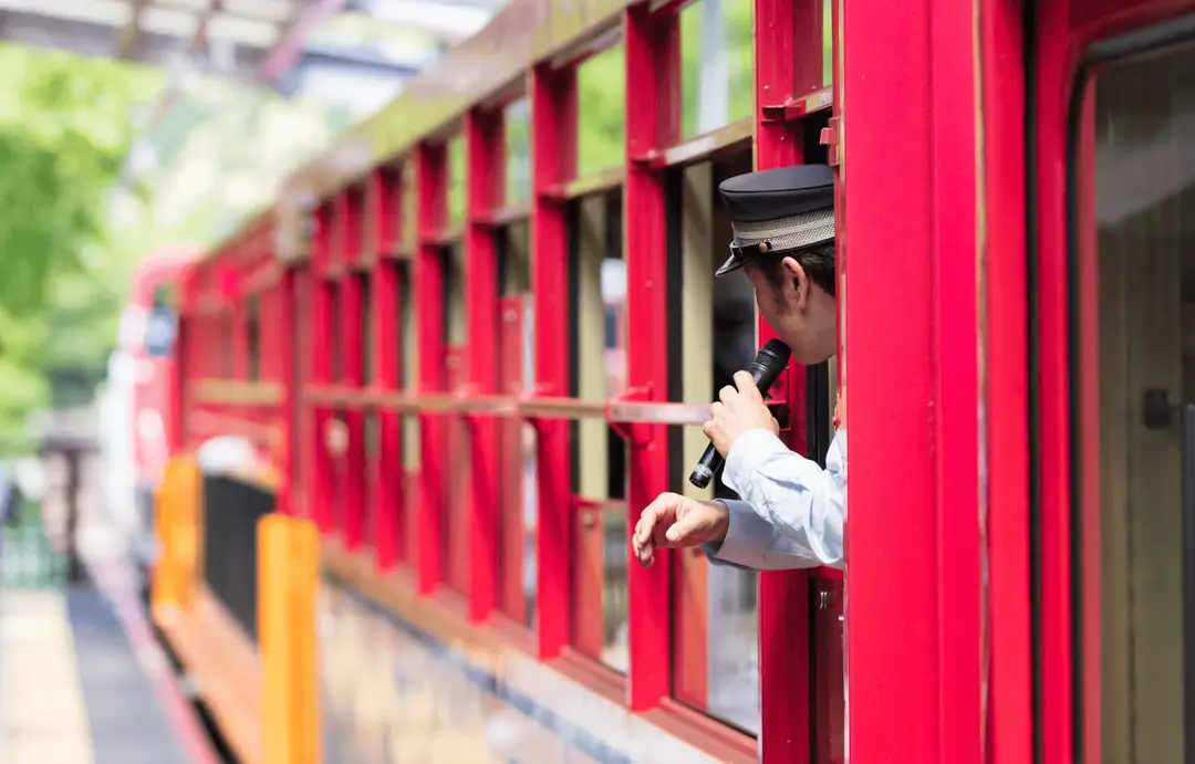 Contrôleur japonais annonçant les paysages de la rivière Hozugawa à bord du Sagano Romantic Train à Arashiyama, une immersion nostalgique et panoramique incluse dans le circuit ferroviaire de Shanti Travel.