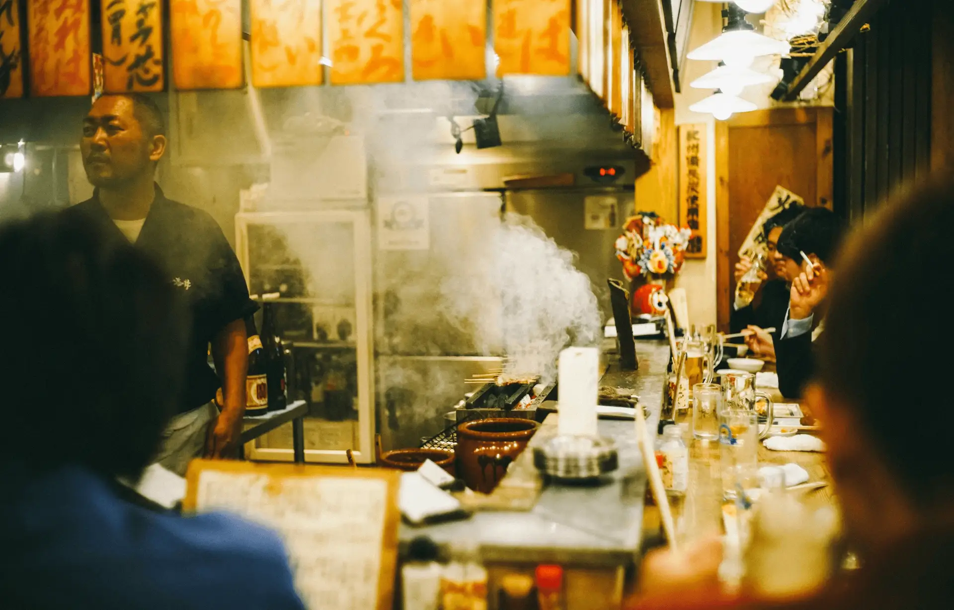 Travel in Asia - A chef serving customers seated around a counter in a small izakaya in Japan