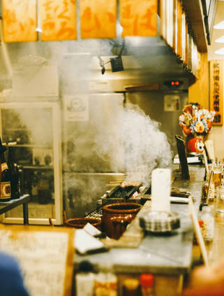 Travel in Asia - A chef serving customers seated around a counter in a small izakaya in Japan