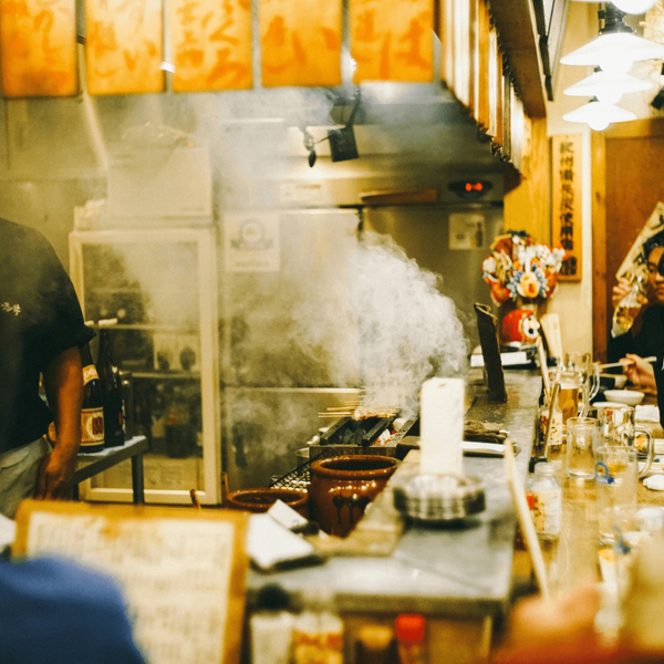 Travel in Asia - A chef serving customers seated around a counter in a small izakaya in Japan
