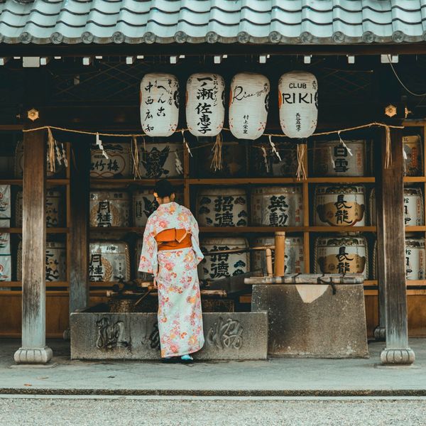 Travel in Asia - A woman in a traditional kimono in front of a Shinto shrine in Japan