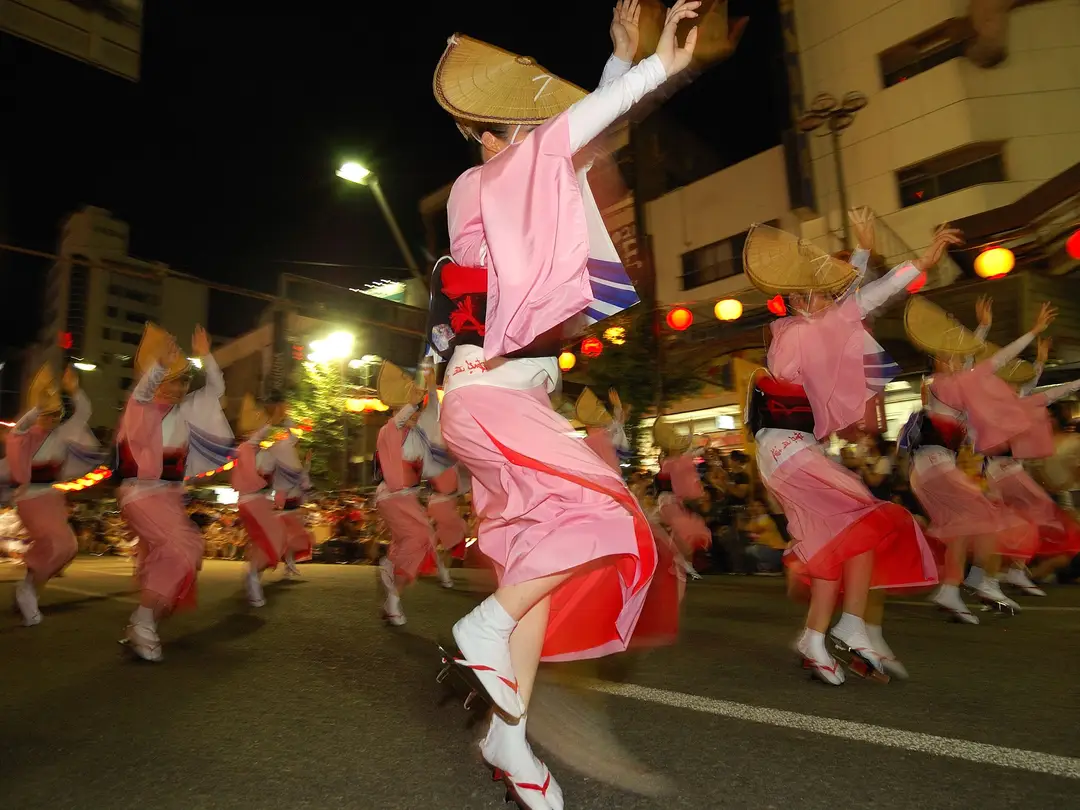 Voyage au Japon – Un groupe de femmes en yukata rose et chapeau de paille traditionnel amigasa exécutant la danse des fous lors du festival Awa Odori à Tokushima.