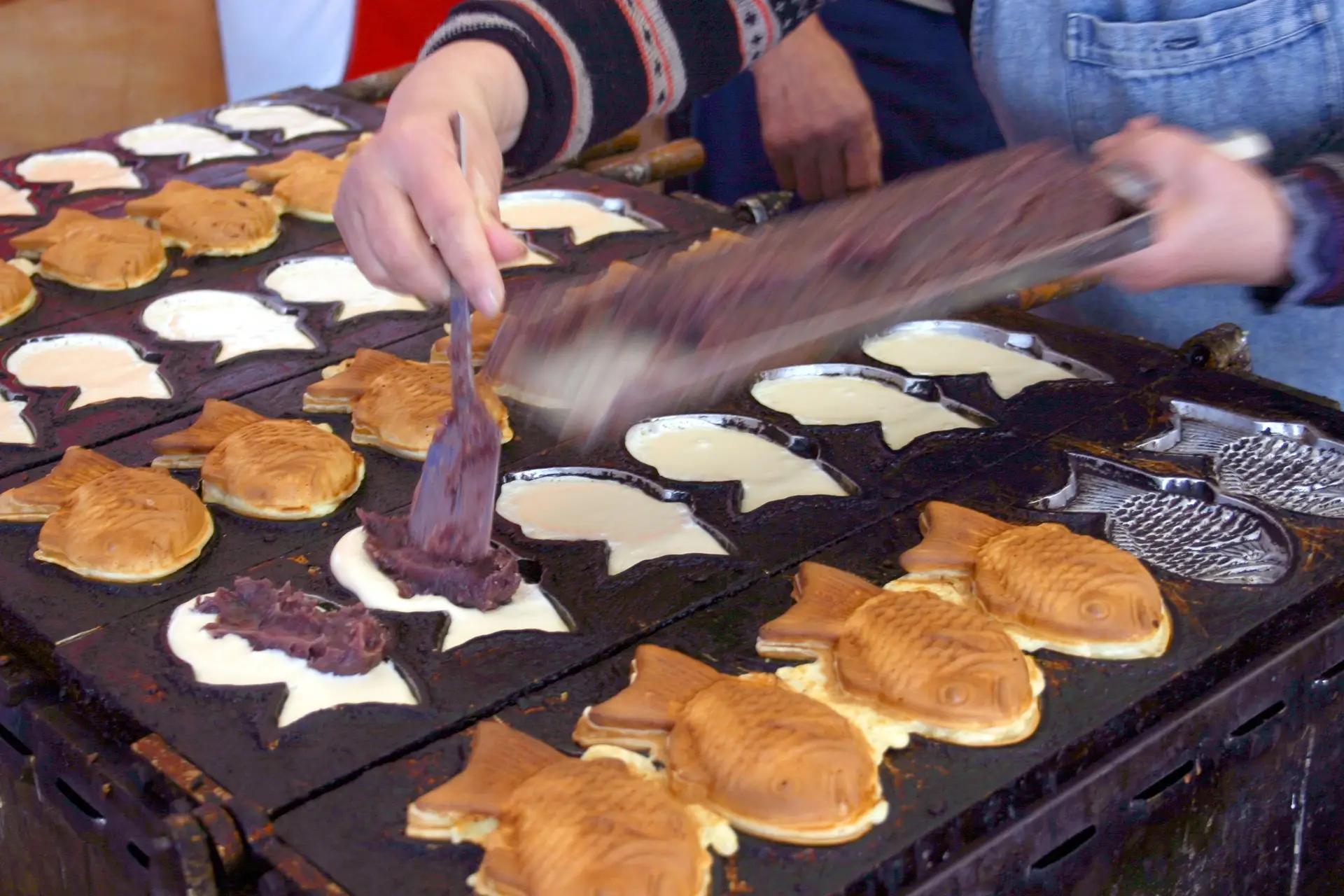 Préparation artisanale de Taiyaki, gâteau traditionnel japonais en forme de poisson fourré à la pâte de haricot rouge azuki.