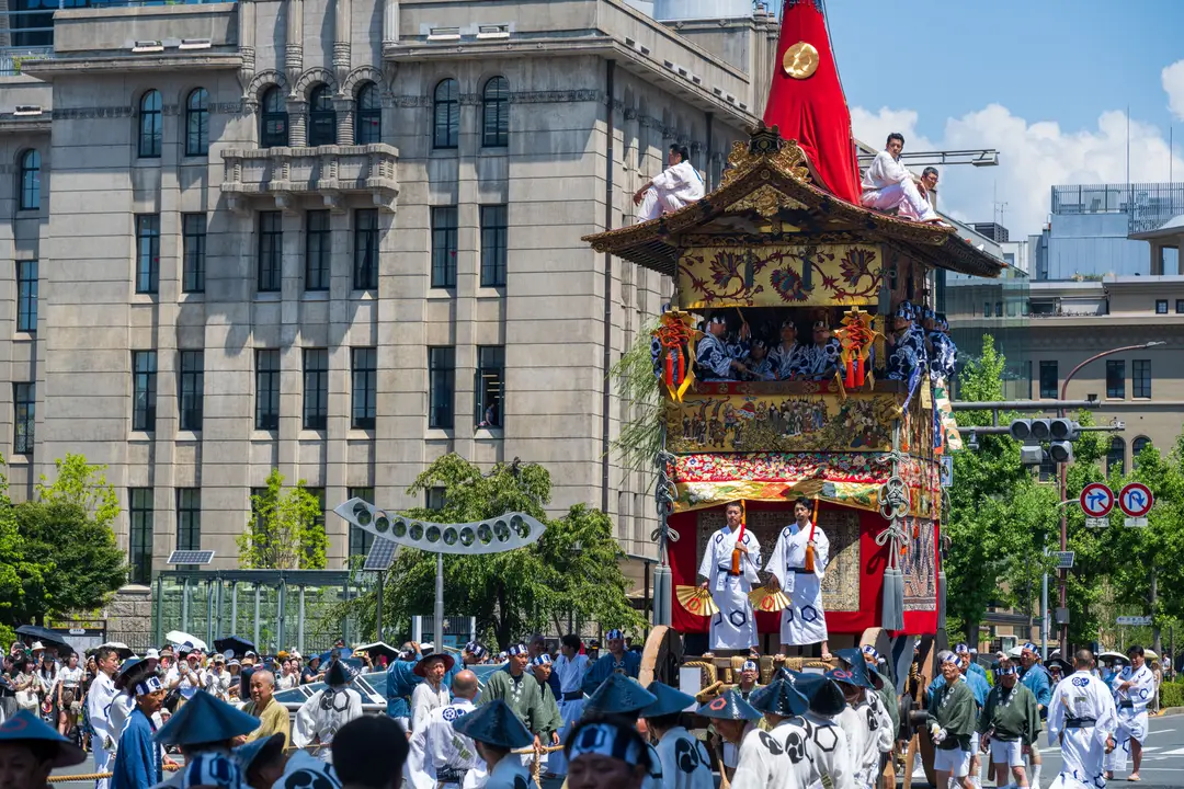 Voyage au Japon – Un immense char traditionnel en bois sculpté et décoré de tissus précieux défilant au milieu de la foule lors du Gion Matsuri à Kyoto.