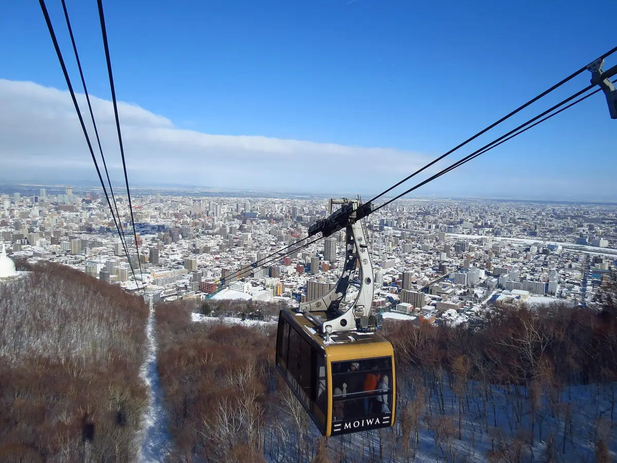 Voyage Japon — Téléphérique montant au sommet du mont Moiwa offrant une vue panoramique sur la ville de Sapporo à Hokkaido.