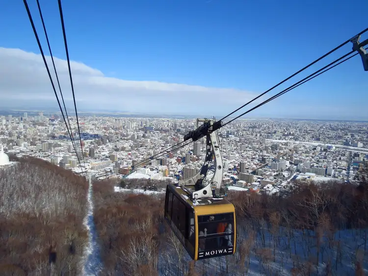 Voyage Japon — Téléphérique montant au sommet du mont Moiwa offrant une vue panoramique sur la ville de Sapporo à Hokkaido.