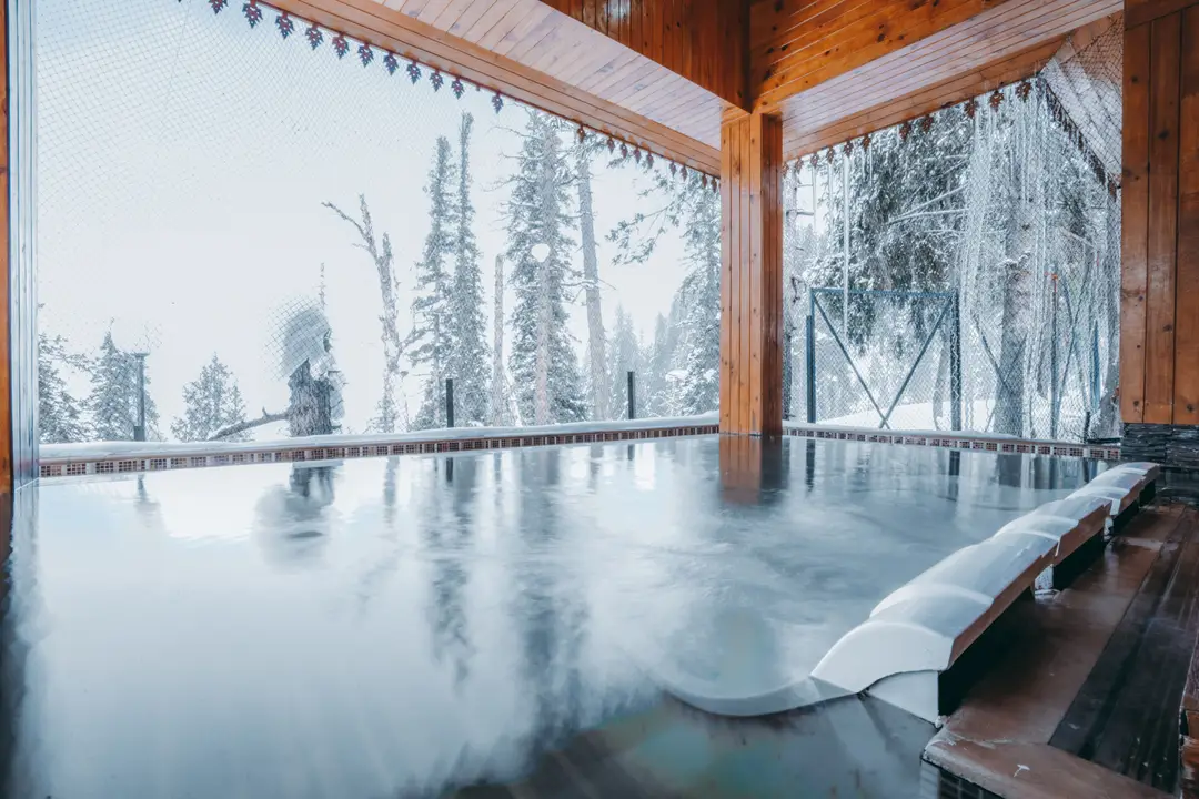 Bain chaud extérieur de type onsen dans un ryokan au Japon entouré d'un paysage enneigé