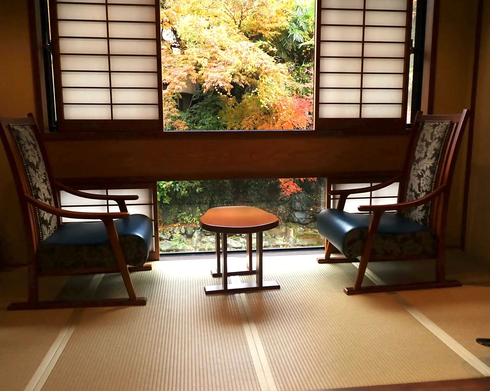 Chambre d'un ryokan avec tatami et chaise devant la fenêtre et momiji.