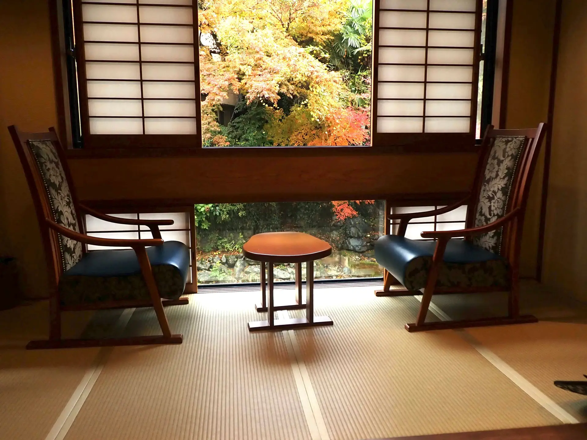 Chambre d'un ryokan avec tatami et chaise devant la fenêtre et momiji.