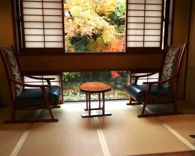 Chambre d'un ryokan avec tatami et chaise devant la fenêtre et momiji.