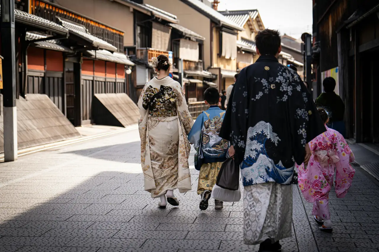 vue de dos d une famille avec enfants portant des kimonos traditionnels marchant dans une ruelle historique aux maisons en bois a kyoto