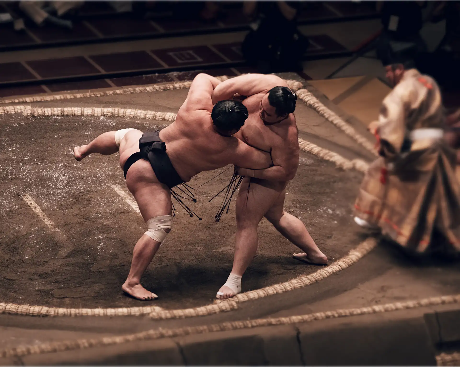 Deux lutteurs de sumo en plein combat lors d'un tournoi traditionnel dans une arène au Japon.