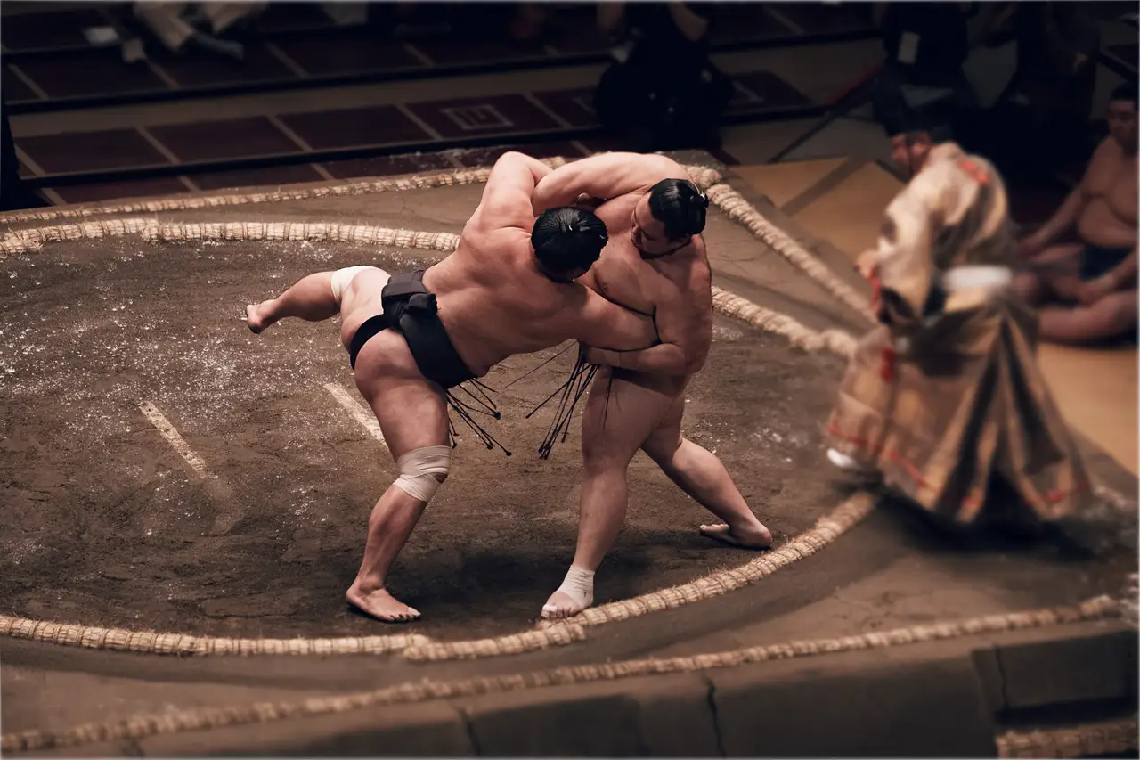 Deux lutteurs de sumo en plein combat lors d'un tournoi traditionnel dans une arène au Japon.