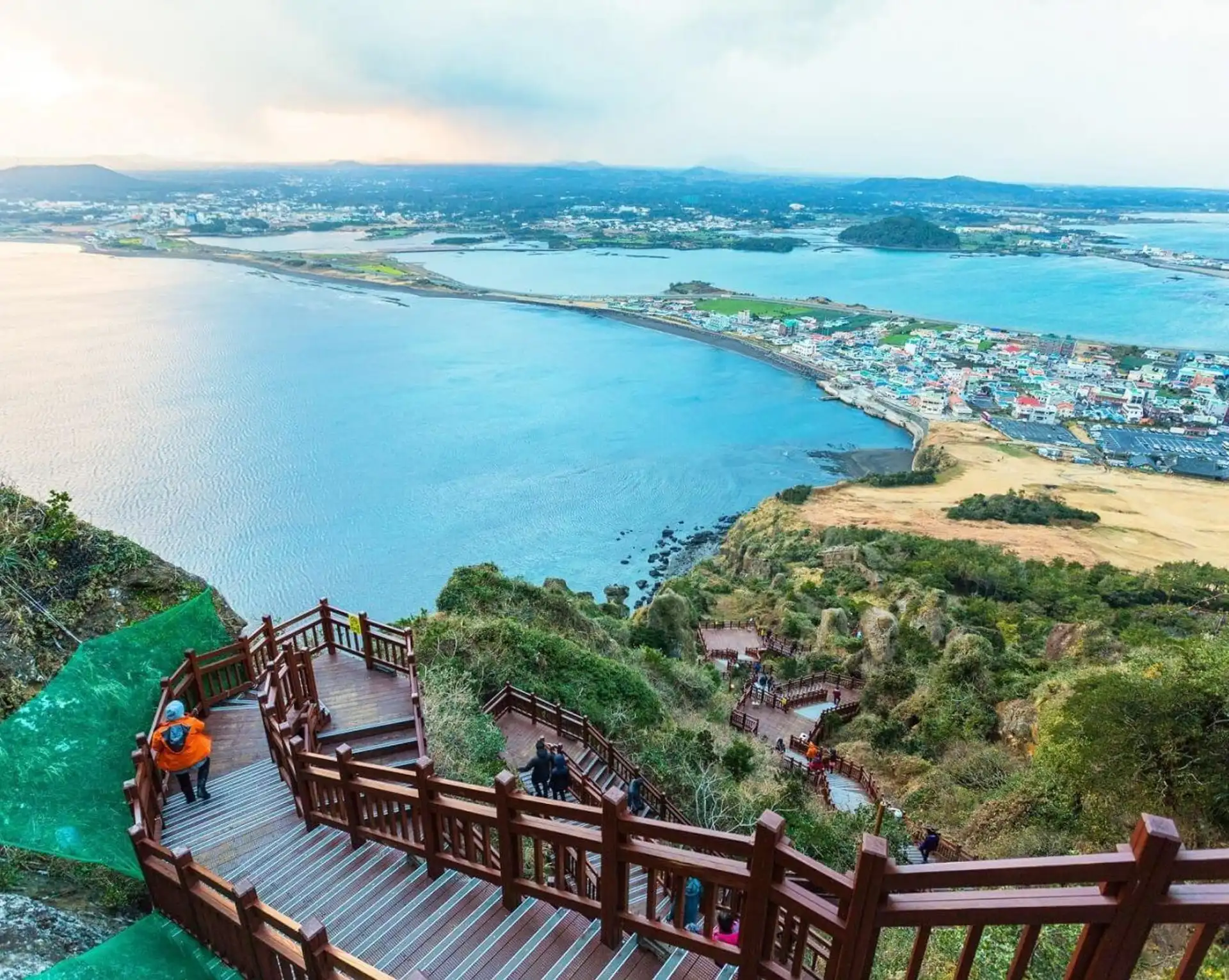 Vue panoramique en hauteur sur l'isthme côtier et la ville de Seongsan entourée par l'océan depuis le sommet du cratère de Seongsan Ilchulbong à Jeju.