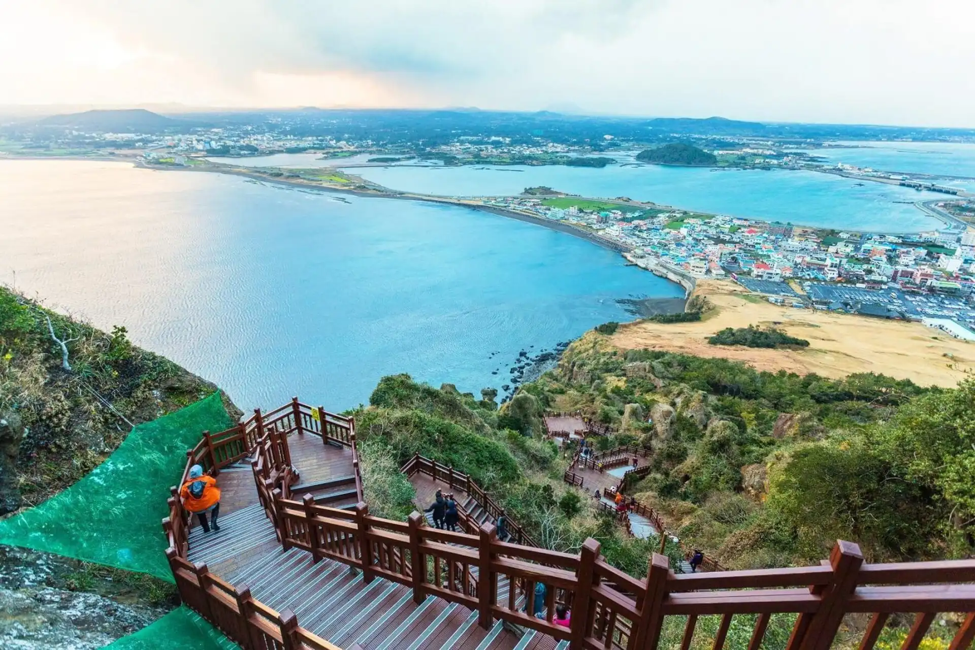 Vue panoramique en hauteur sur l'isthme côtier et la ville de Seongsan entourée par l'océan depuis le sommet du cratère de Seongsan Ilchulbong à Jeju.