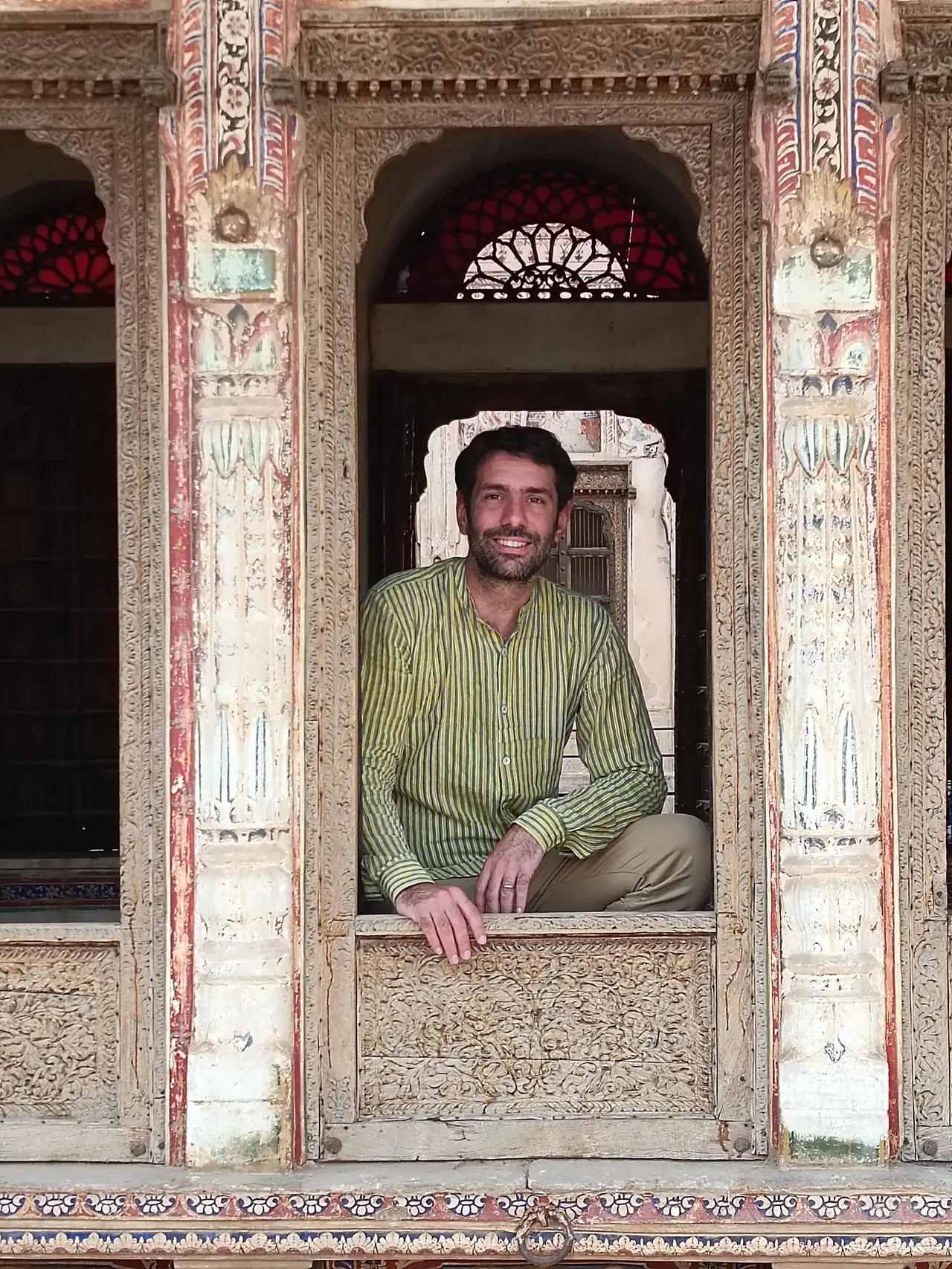 Portrait de Jérémy Grasset, co-fondateur et directeur de l'agence de voyage Shanti Travel, assis devant une arche sculptée traditionnelle en Inde.