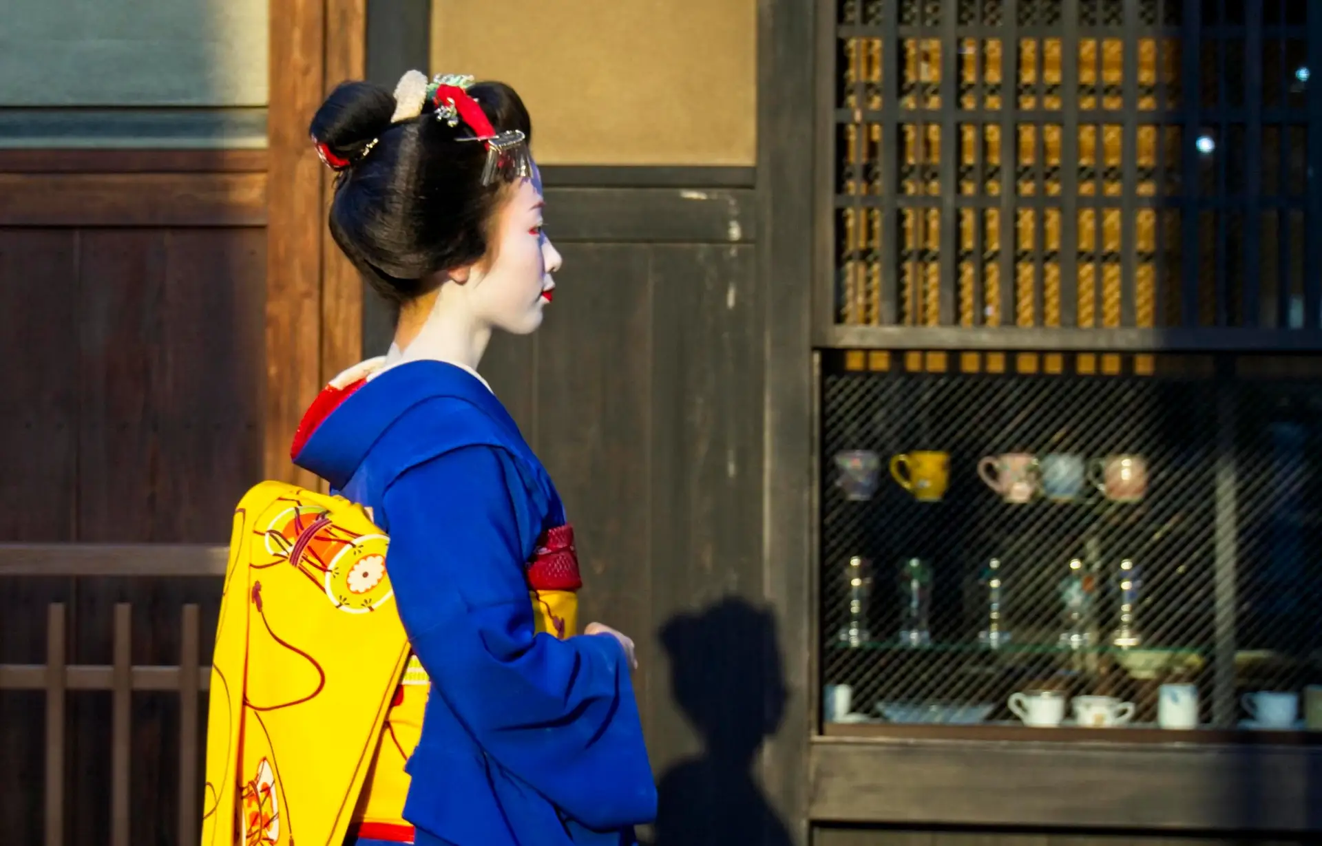 Figure emblématique du Japon — Une Maiko en kimono traditionnel marchant devant une maison de thé à Gion, Kyoto.