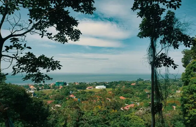 Une vue panoramique depuis une colline verdoyante et arborée s'ouvrant sur le littoral et la mer calme à l'horizon à Kep au Cambodge.