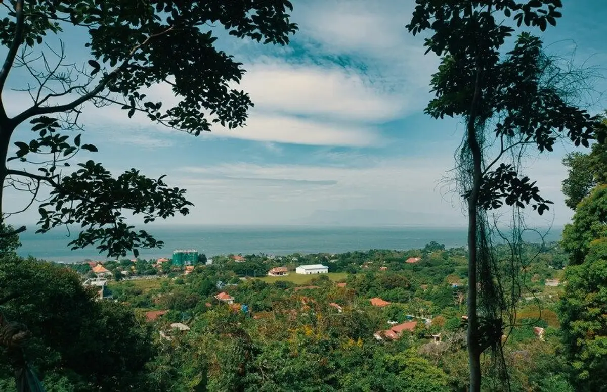 Une vue panoramique depuis une colline verdoyante et arborée s'ouvrant sur le littoral et la mer calme à l'horizon à Kep au Cambodge.