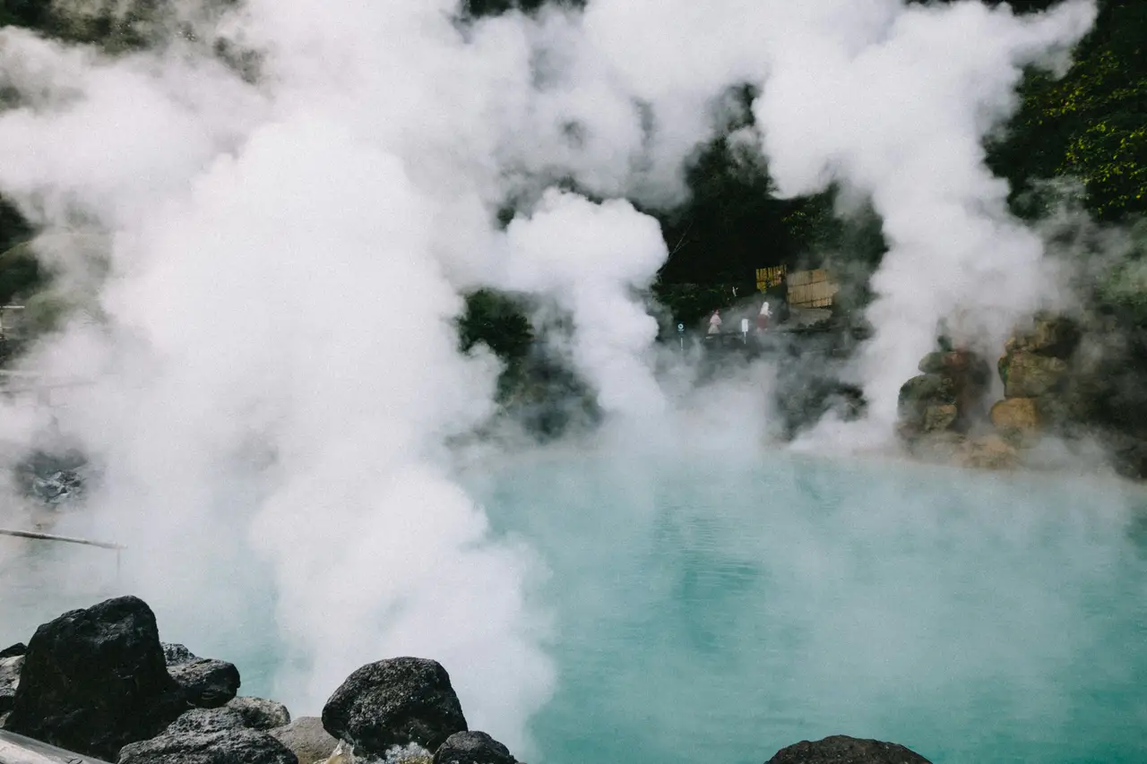 thick white steam rising from the turquoise thermal waters of umi jigoku hot spring surrounded by green vegetation in beppu kyushu