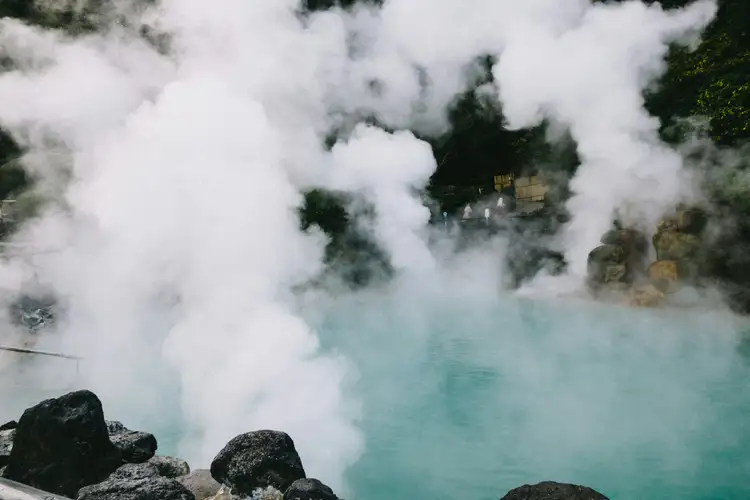 thick white steam rising from the turquoise thermal waters of umi jigoku hot spring surrounded by green vegetation in beppu kyushu