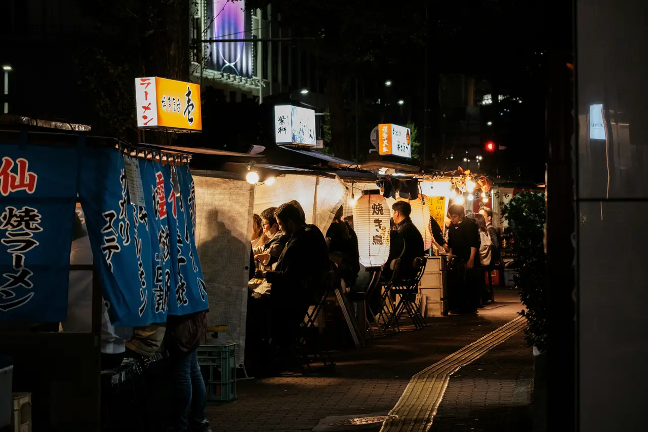 illuminated traditional yatai street food stalls at night with customers dining outdoors in fukuoka before departure