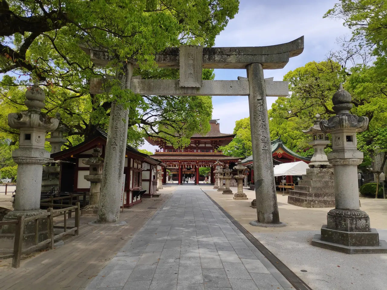 traditional stone torii gate at the entrance of the sacred dazaifu tenmangu shrine surrounded by green trees in kyushu