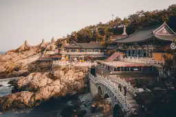 Vue panoramique d'un temple bouddhiste paisible situé en bord de mer à Busan, invitant à la découverte de la Corée du Sud.