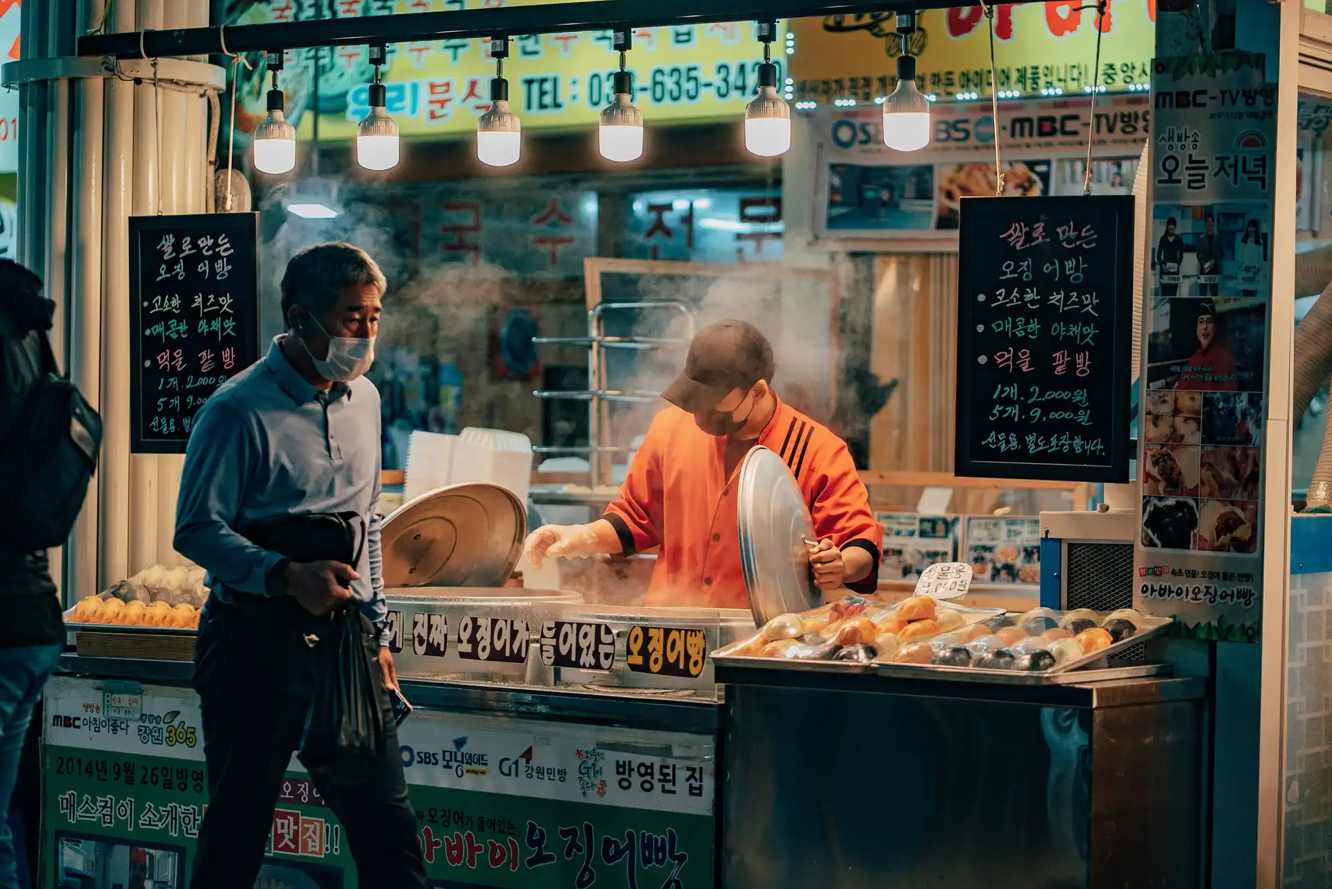 Un stand de street food traditionnel fumant dans une rue coréenne en soirée, symbolisant la richesse culinaire et la convivialité du pays.