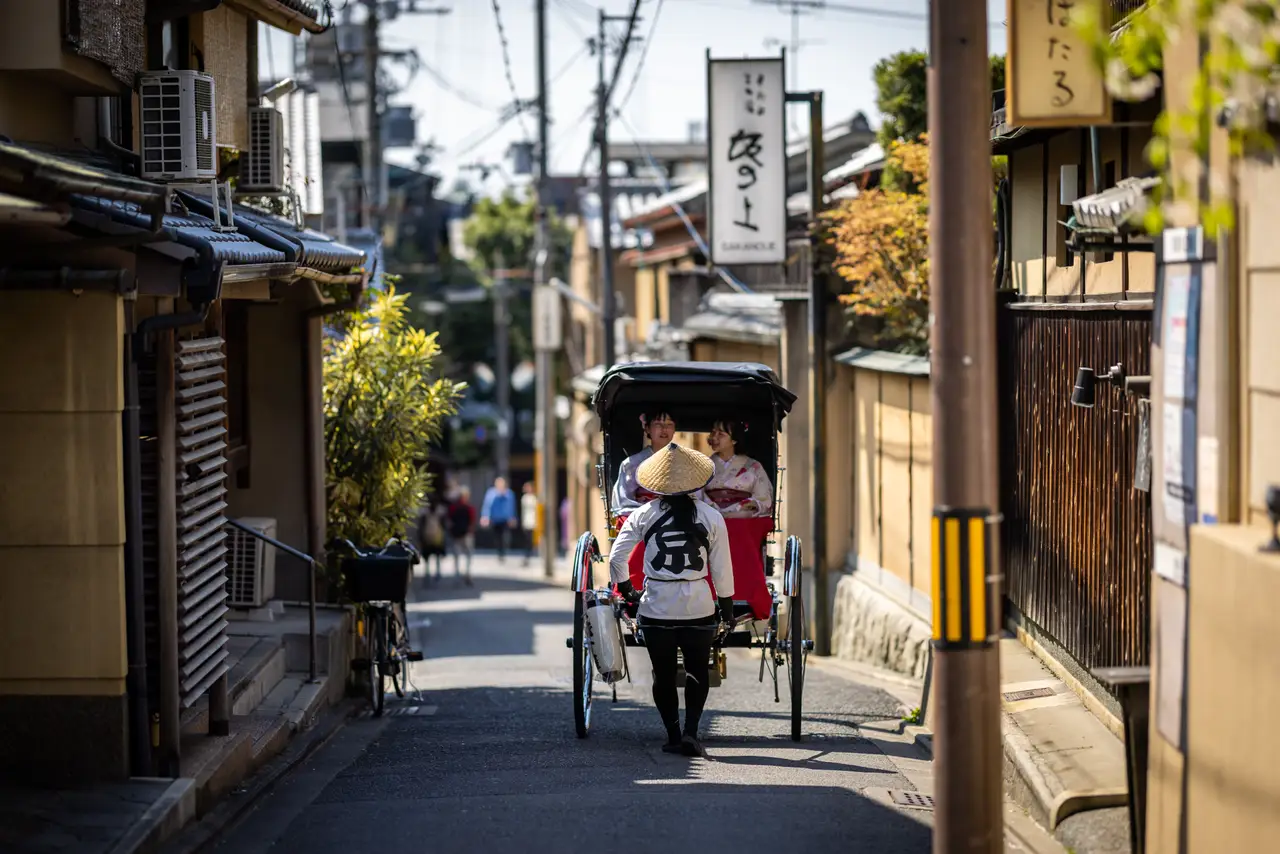Voyage en Asie – Un pousse-pousse traditionnel circule dans une ruelle en bois préservée du quartier historique de Gion à Kyoto au Japon.