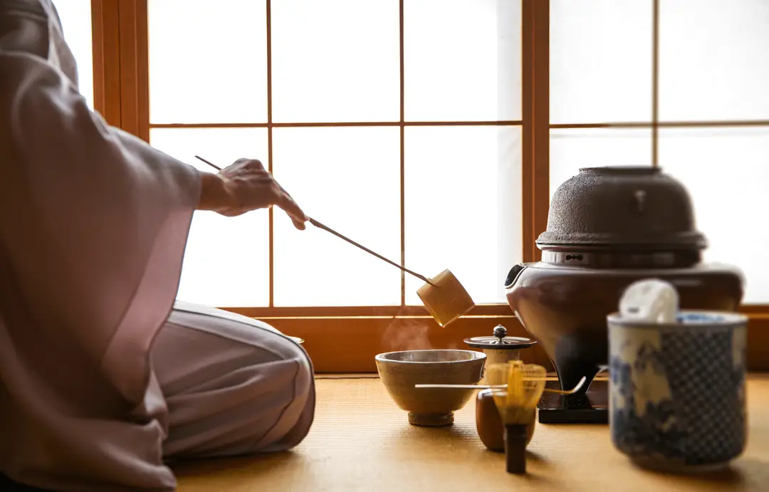 Route du thé au Japon – Maître de thé versant de l'eau chaude avec une louche en bambou lors de la préparation du matcha.
