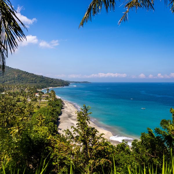 Une plage de Senggigi où l’on peut voir un magnifique dégradé de bleu ainsi qu’une végétation luxuriante.