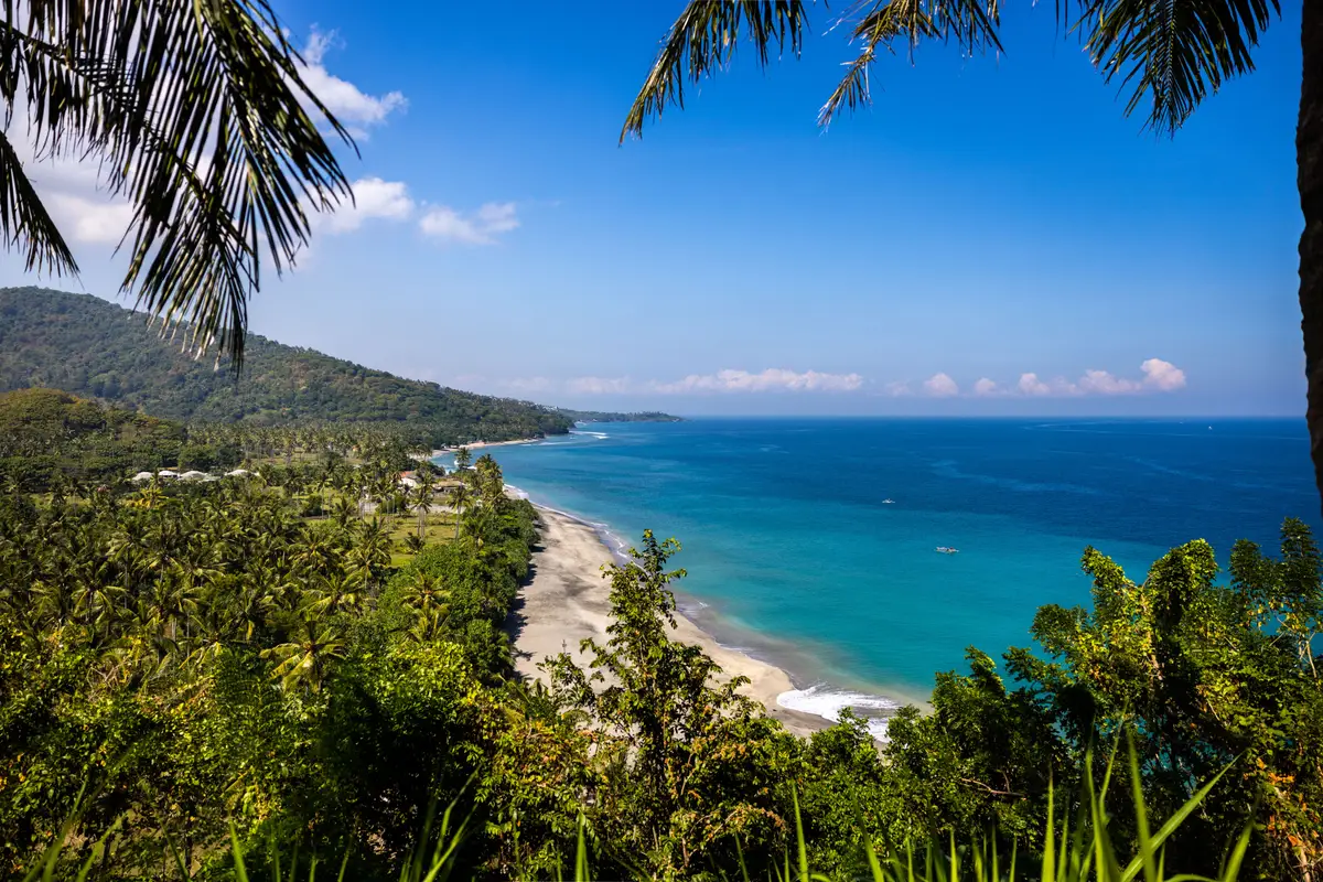 Une plage de Senggigi où l’on peut voir un magnifique dégradé de bleu ainsi qu’une végétation luxuriante.