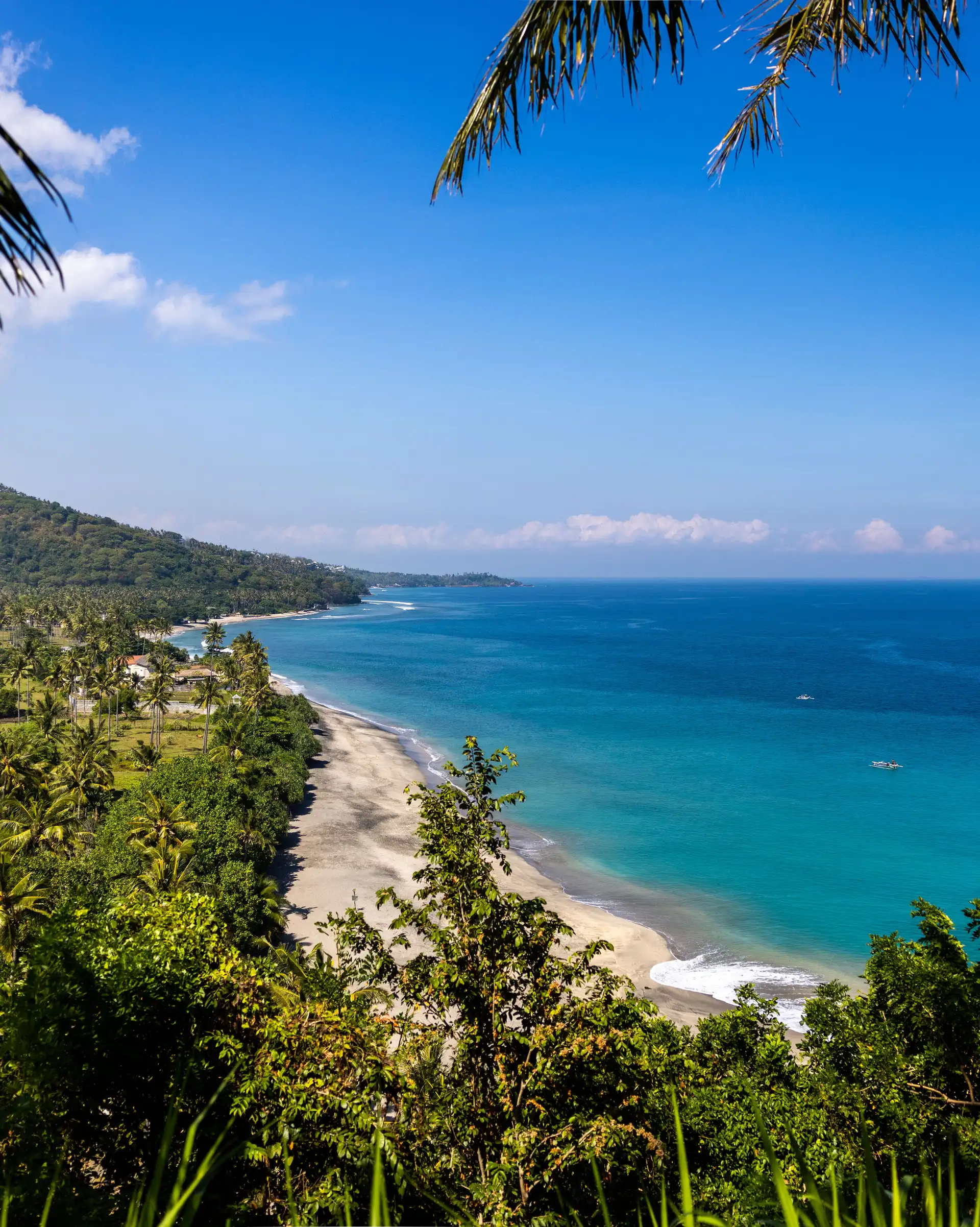 Une plage de Senggigi où l’on peut voir un magnifique dégradé de bleu ainsi qu’une végétation luxuriante.