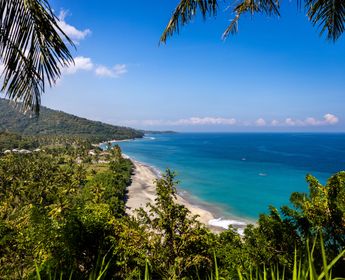 Une plage de Senggigi où l’on peut voir un magnifique dégradé de bleu ainsi qu’une végétation luxuriante.
