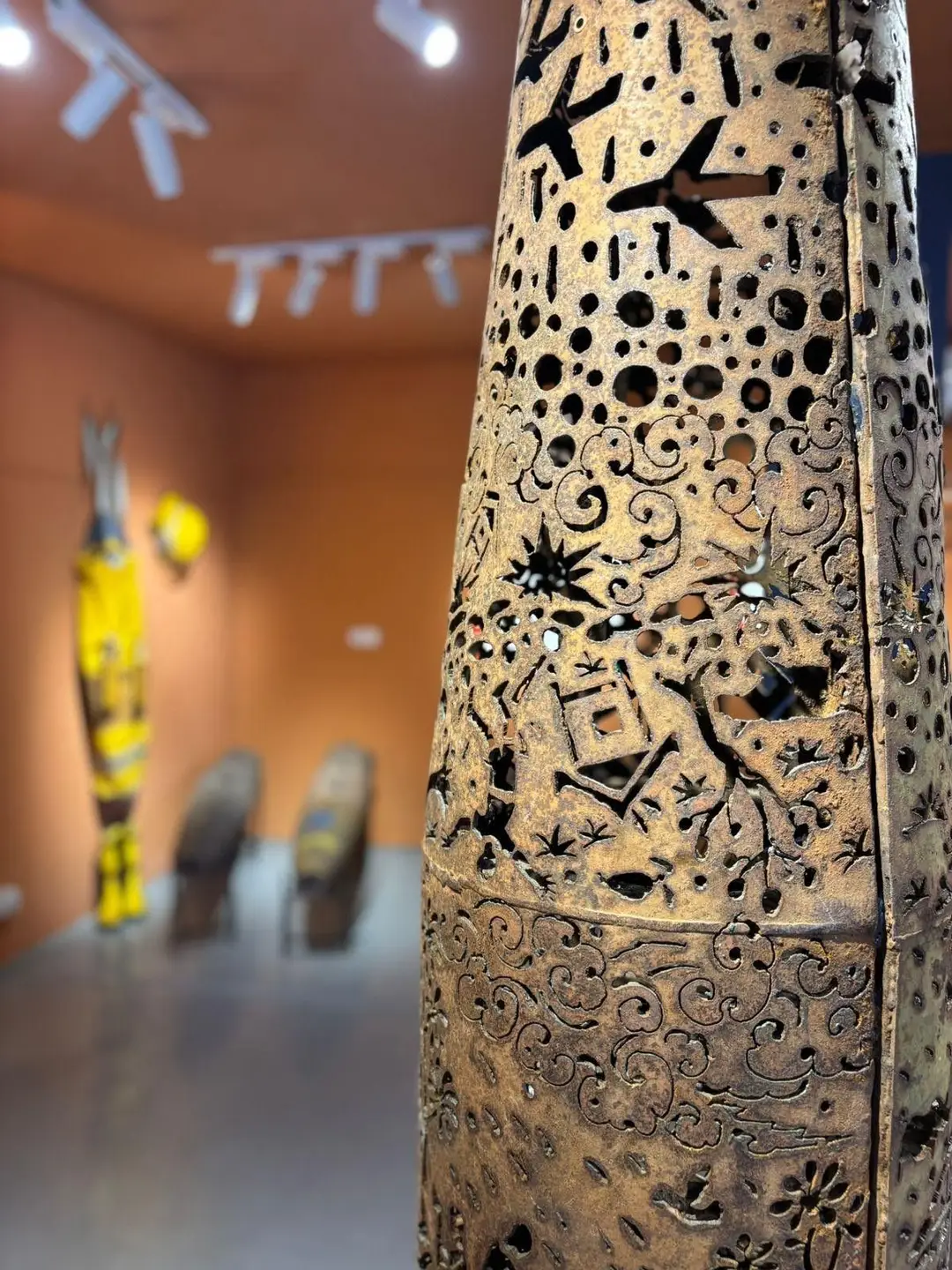 Gros plan sur une carcasse d'obus sculptée et ciselée d'ajours décoratifs, exposée au premier plan dans un musée d'histoire au Laos.
