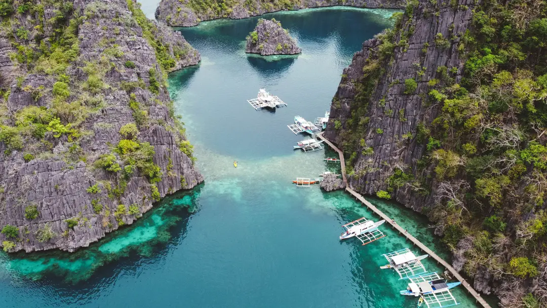 Magnifique cliché aérien de bateaux dans des eaux cristallines entourées de falaises rocheuses à Coron, Philippines.jpg