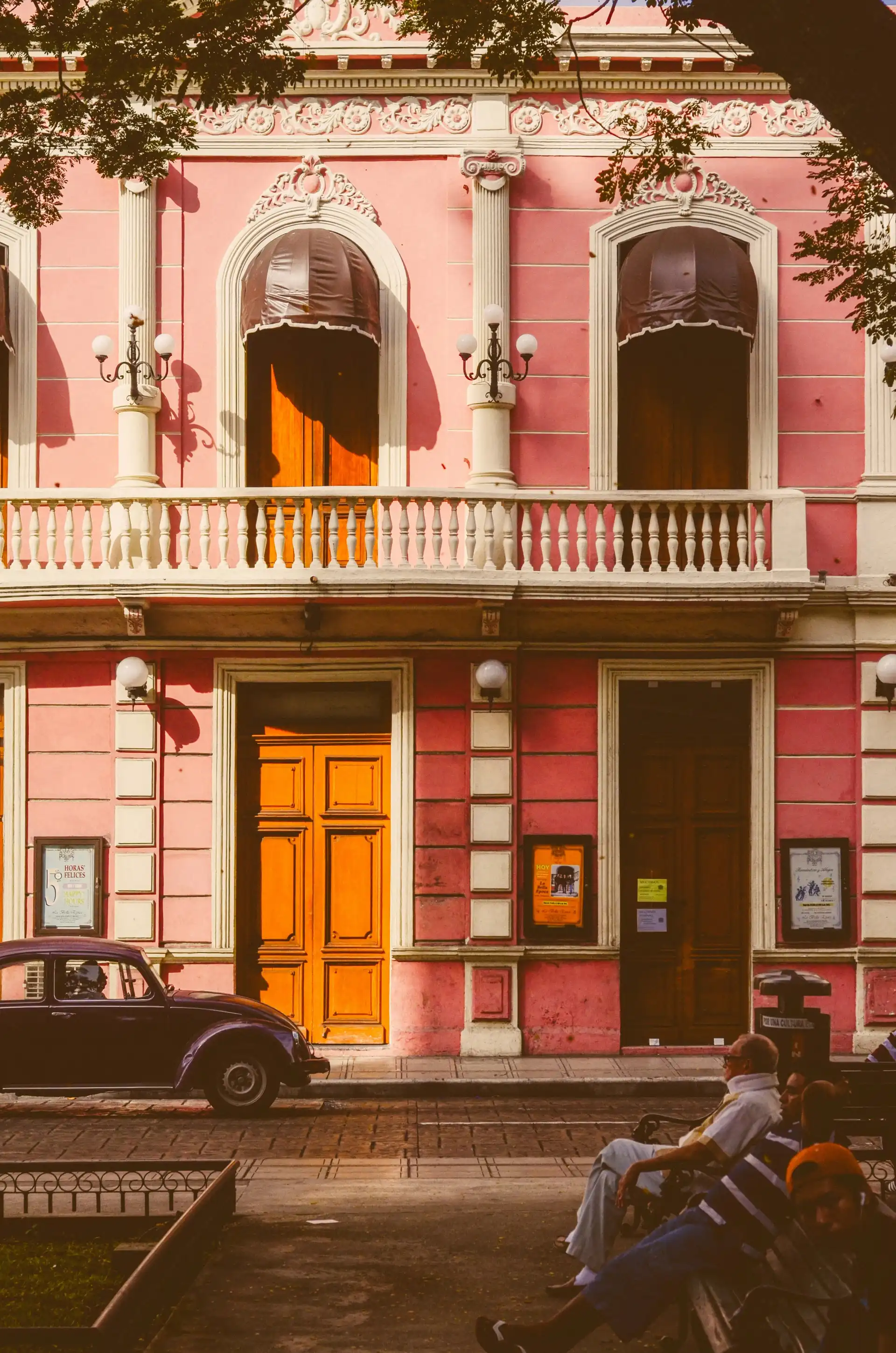 Voyage au Mexique – Façade à l'architecture coloniale d'une grande maison rose avec balcon et fenêtres cintrées à Mérida dans le Yucatán.