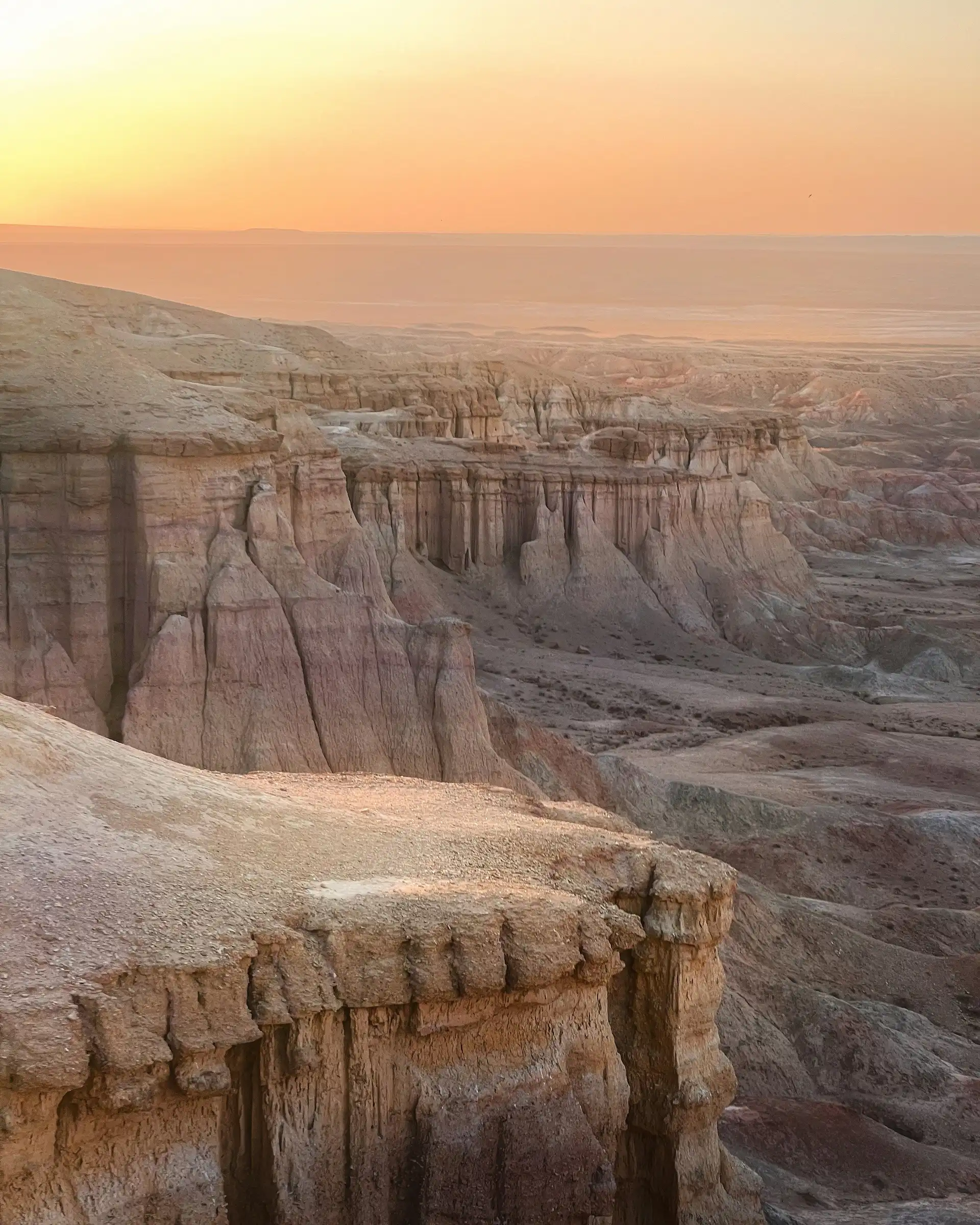 formation rocheuse et falaises creusees du desert de gobi au coucher du soleil sous un ciel orange en mongolie