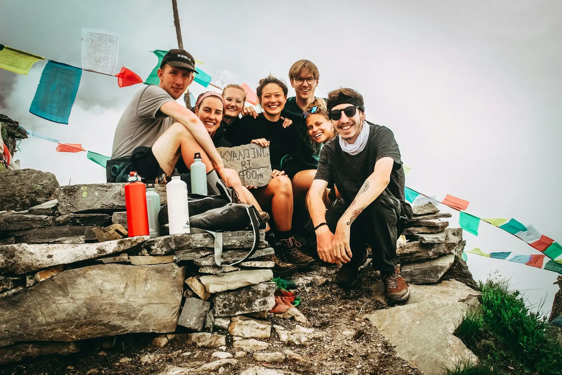Travel in Asia - Group of friends smiling for a photograph after a hike in Nepal with prayer flags in background