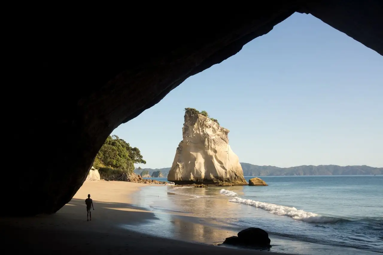 Vue depuis l'intérieur d'une grotte marine sur la célèbre arche naturelle et le piton rocheux de Cathedral Cove.