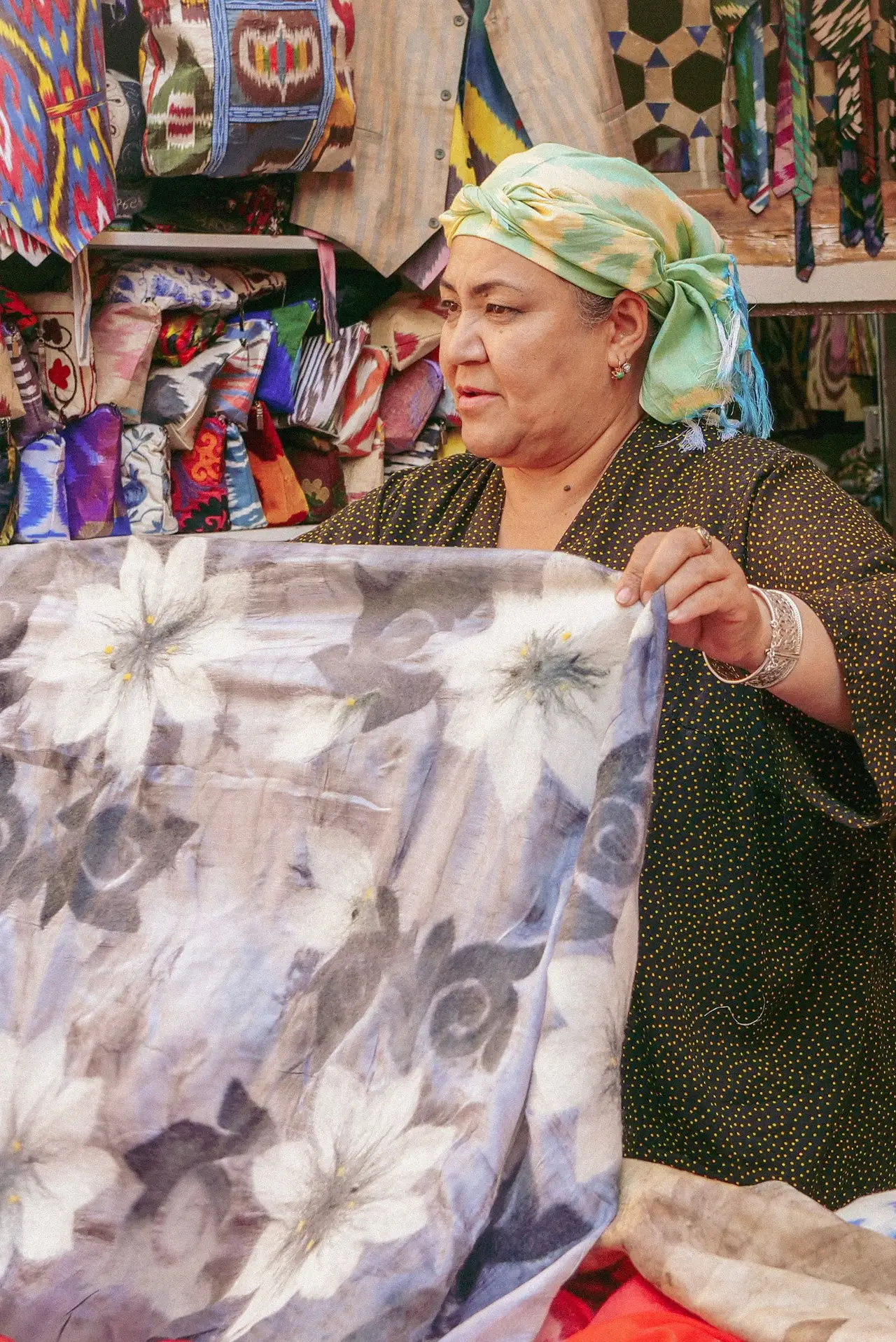 une femme marchande ouzbeke presentant un grand tissu traditionnel de soie au marche de boukhara en ouzbekistan