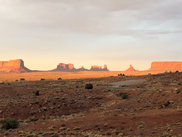 Vue panoramique sur les buttes et mesas de grès rouge de Monument Valley éclairées par la lumière dorée en terre Navajo