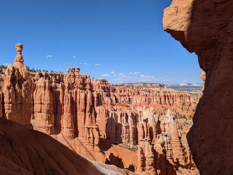 Formations géologiques de hoodoos et cheminées de fée ocres et blanches dans l'amphithéâtre de Bryce Canyon sous un ciel bleu