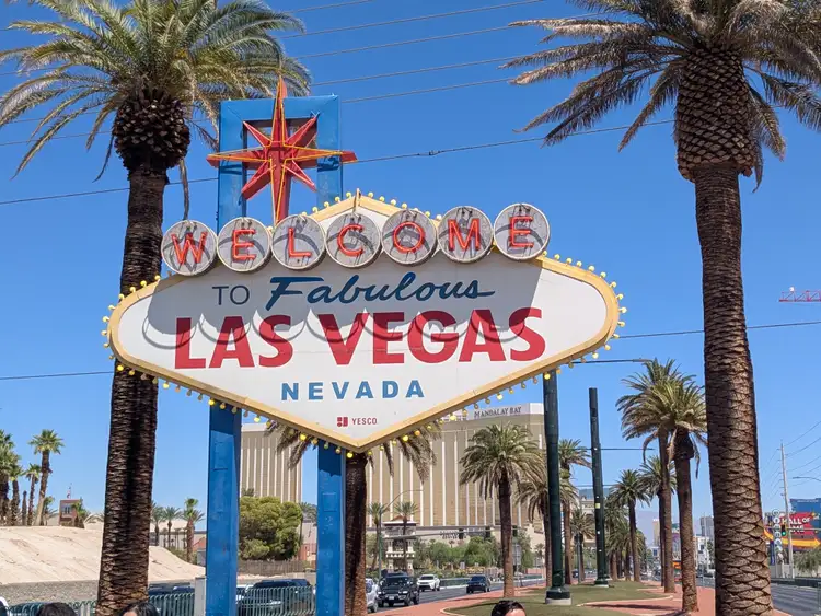 Célèbre panneau rétro Welcome to Fabulous Las Vegas encadré de palmiers sous un ciel bleu