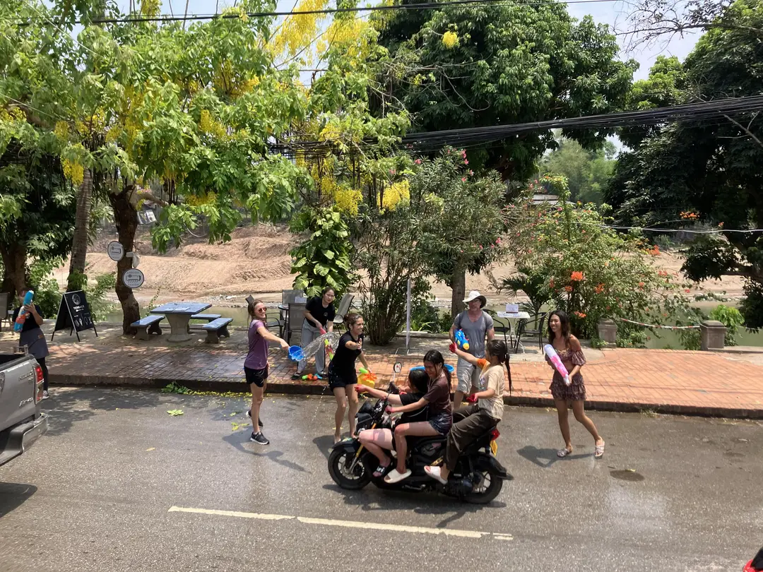 Personnes s'arrosant d'eau dans la rue avec des pistolets à eau et des seaux pendant la fête de Pi Mai Lao.