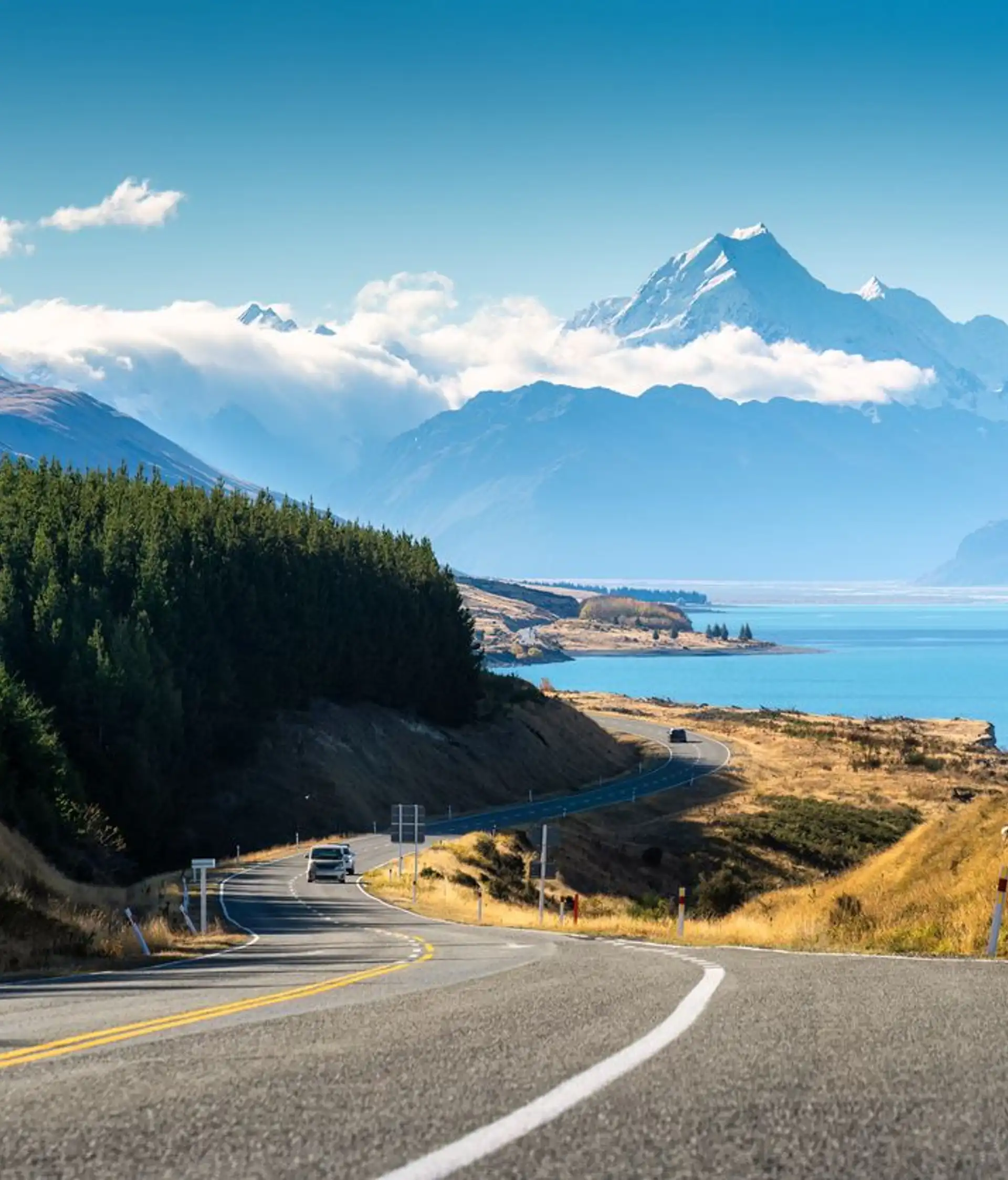 Route panoramique longeant le lac Pukaki aux eaux turquoise avec la majestueuse chaîne de montagnes du Mont Cook en Nouvelle-Zélande.