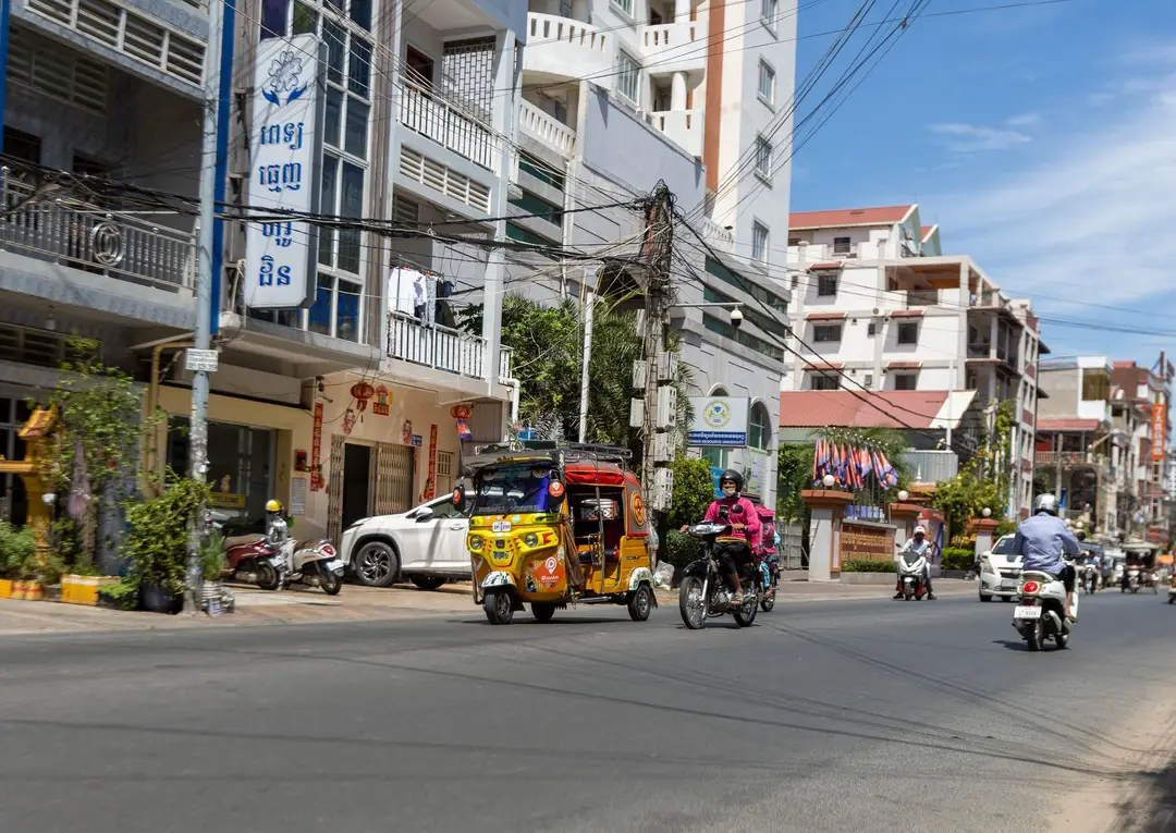Rue vibrante à Phnom Penh présentant des tuk-tuks, des scooters et une vie urbaine animée